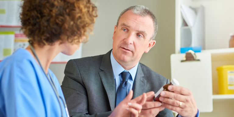 A group of nurses stands together in front of a large window, smiling and dressed in scrubs, showcasing teamwork in healthcare.