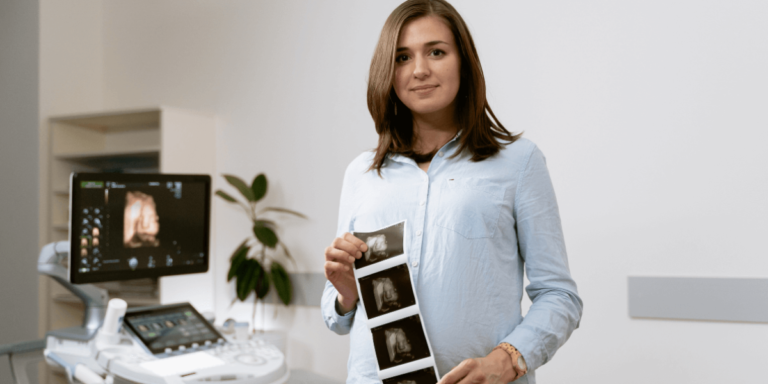 A woman proudly holds her ultrasound photo, smiling as she shares her pregnancy news.