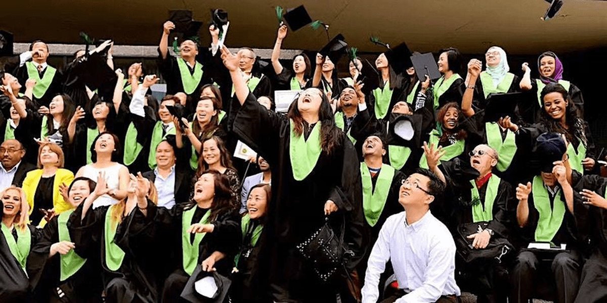 A group of graduates wearing green and black gowns, celebrating their academic achievements.